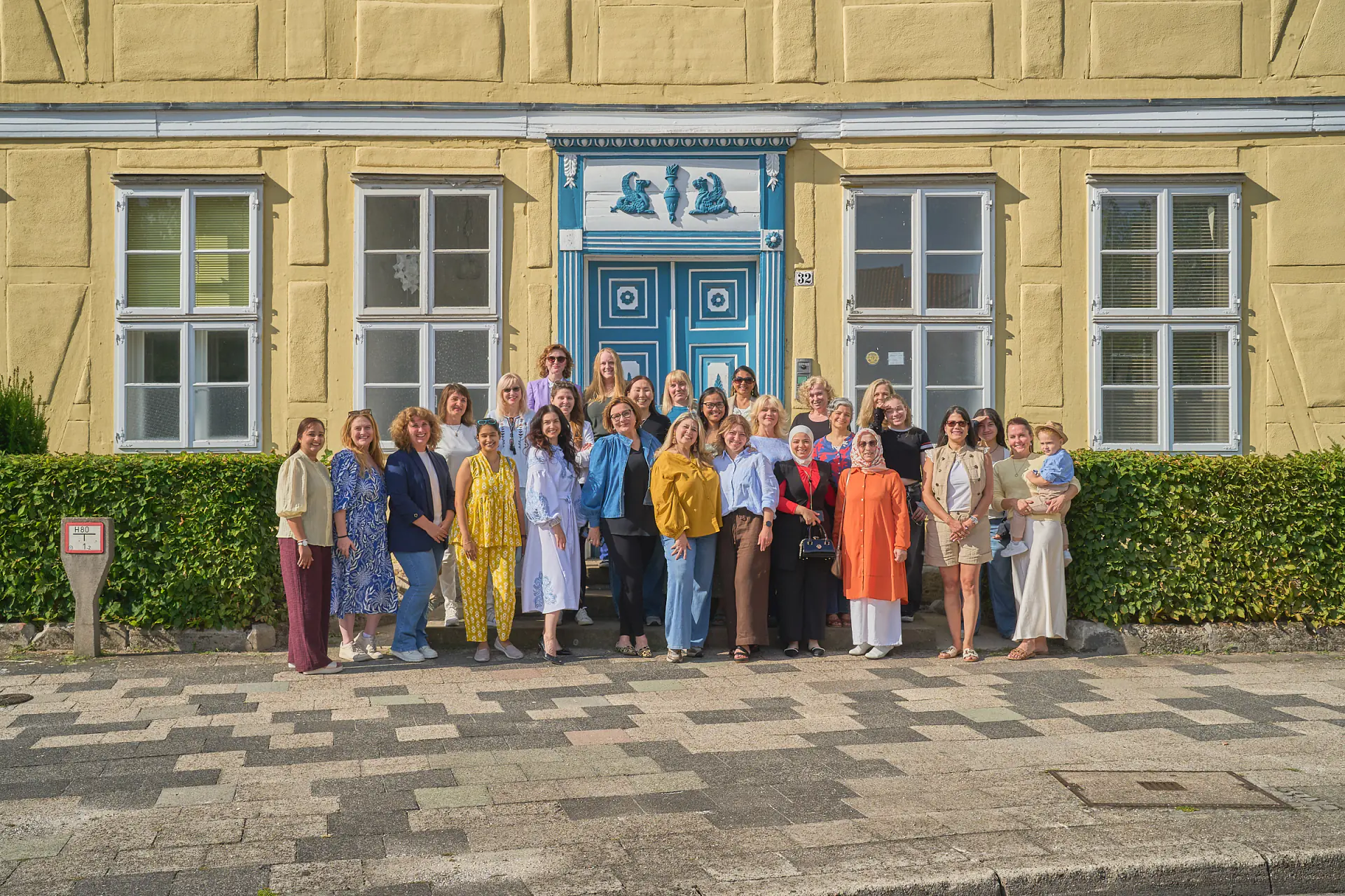 Rund dreißig Frauen stehen vor der gelben Fassade und der blauen Haustür der Trift 32 und schauen in die Kamera.