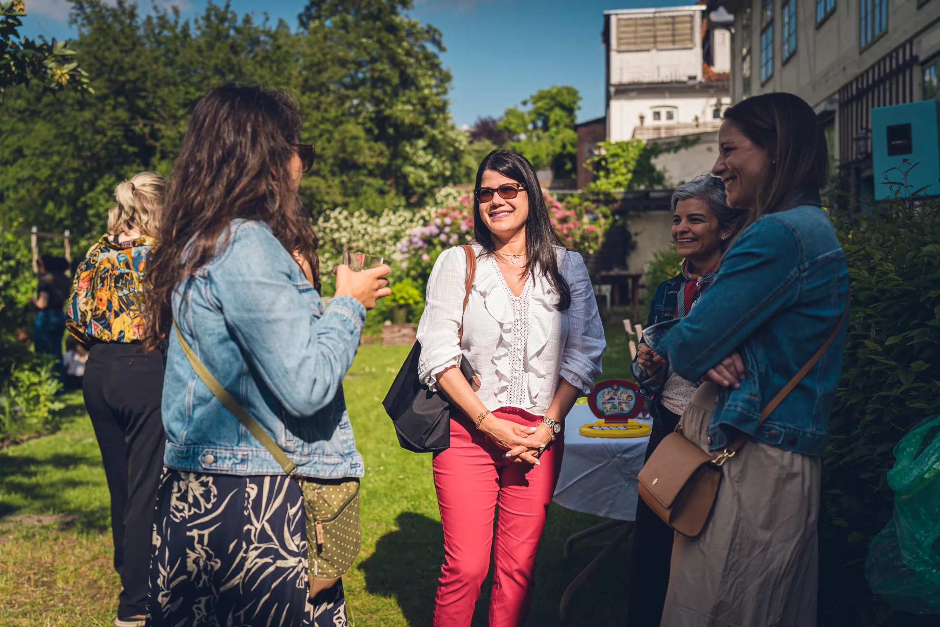 Women standing together in the sunny garden, talking.