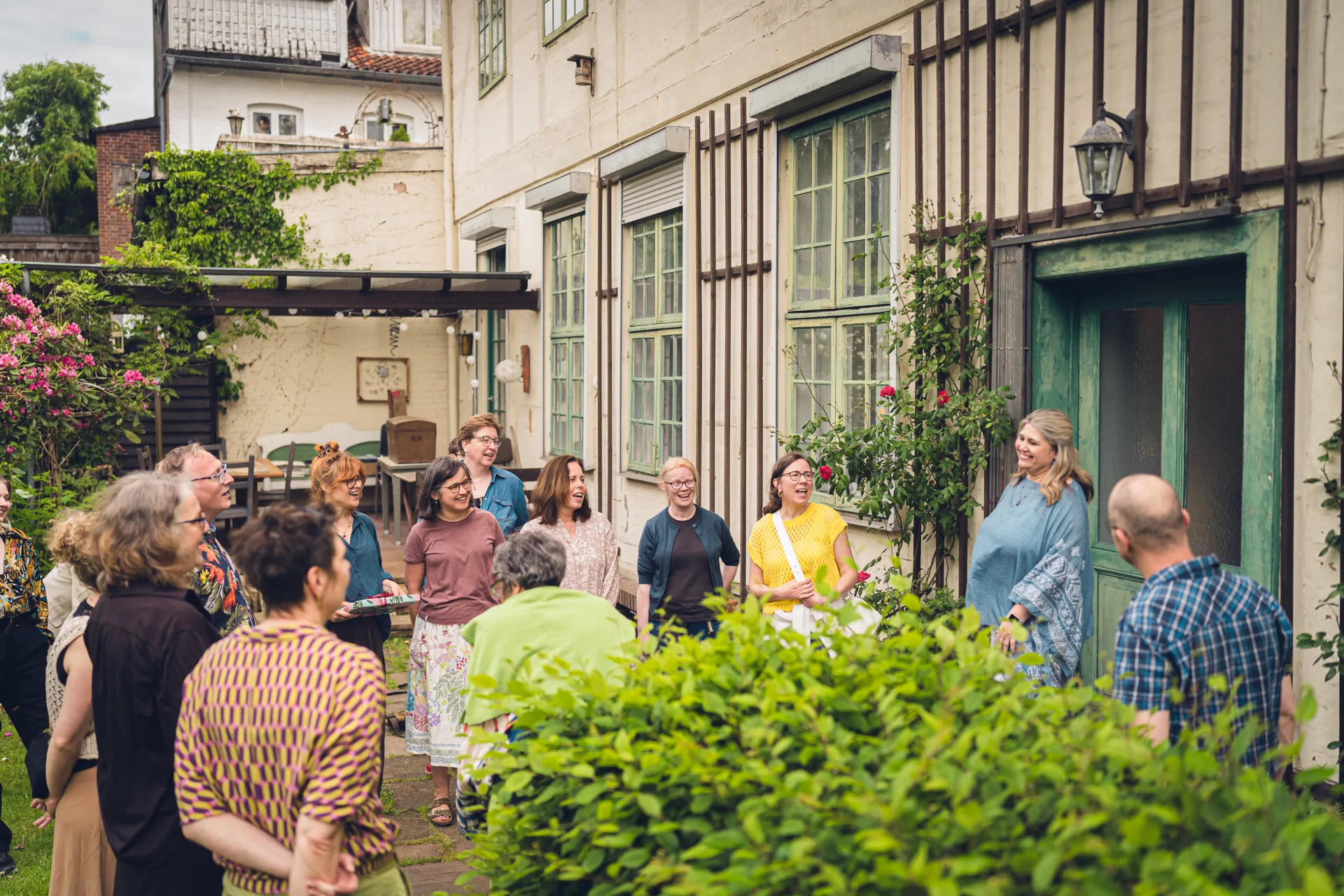 A large group stands together laughing in the courtyard at Trift 32.