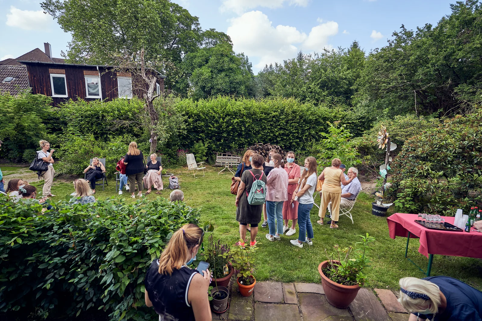 Viele Menschen stehen im sommerlichen Garten zusammen.
