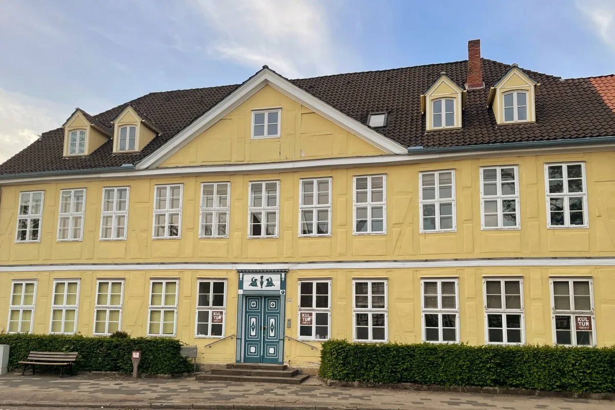 Gelb verputztes Barockhaus mit Sprossenfenstern und blauer Haustür.