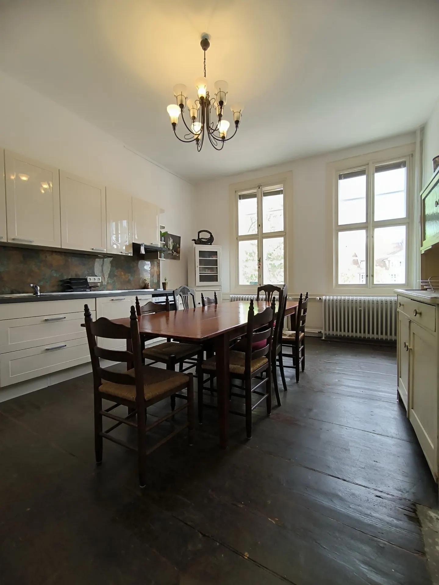 The large kitchen with a long table and open shelves.