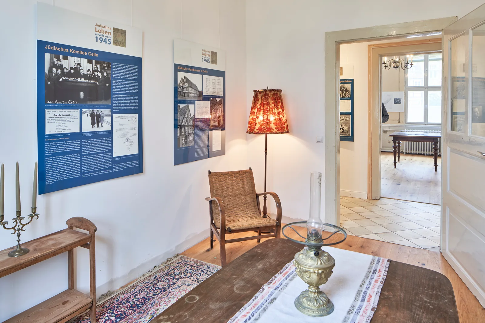 Raum mit Ausstellungstafeln, Sessel und gedecktem Tisch.