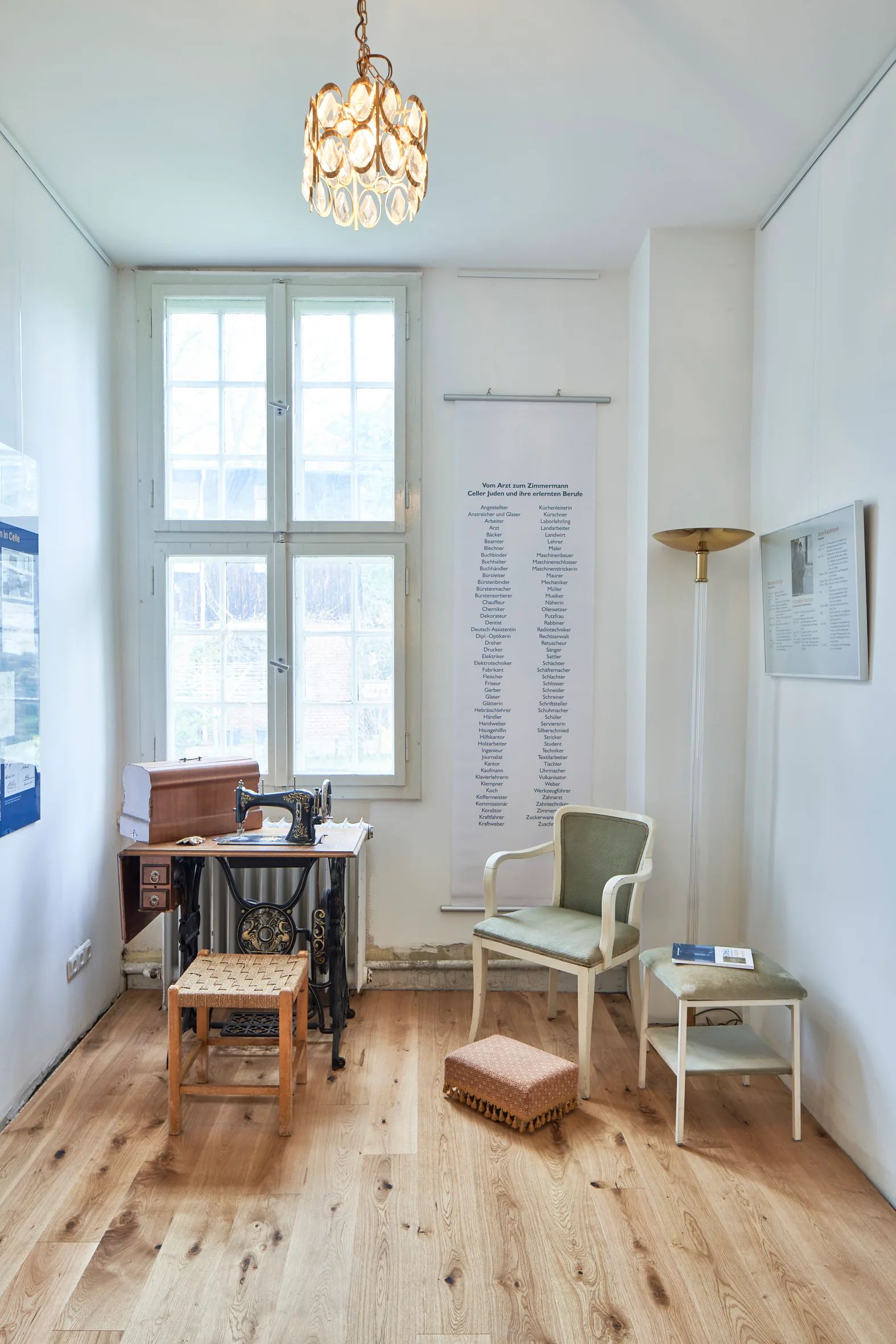 Helles Zimmer mit Sekretär, Sessel und hohem Sprossenfenster.