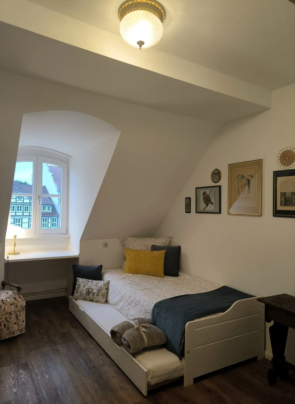 Kleines Zimmer unter der Dachschräge mit Tagesbett am Fenster.
