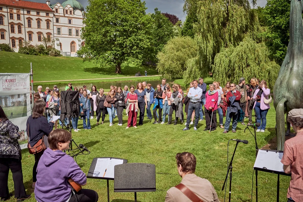 Publikum bei einer Veranstaltung im Garten, im warmen Gegenlicht.