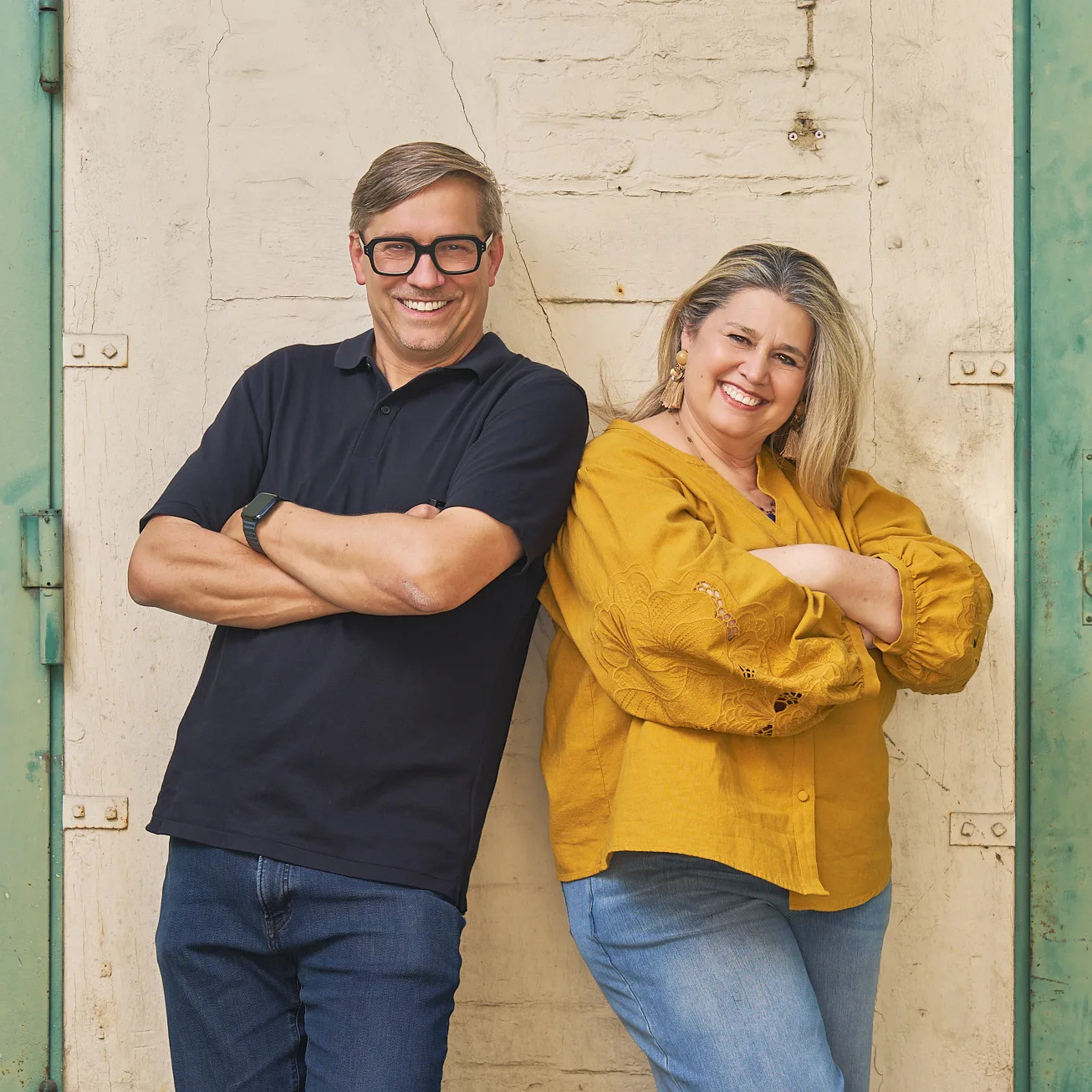 Zandra Gröschner Rico del Valle und Roman Thomas lehnen Rücken an Rücken an einer alten Tür und lachen.