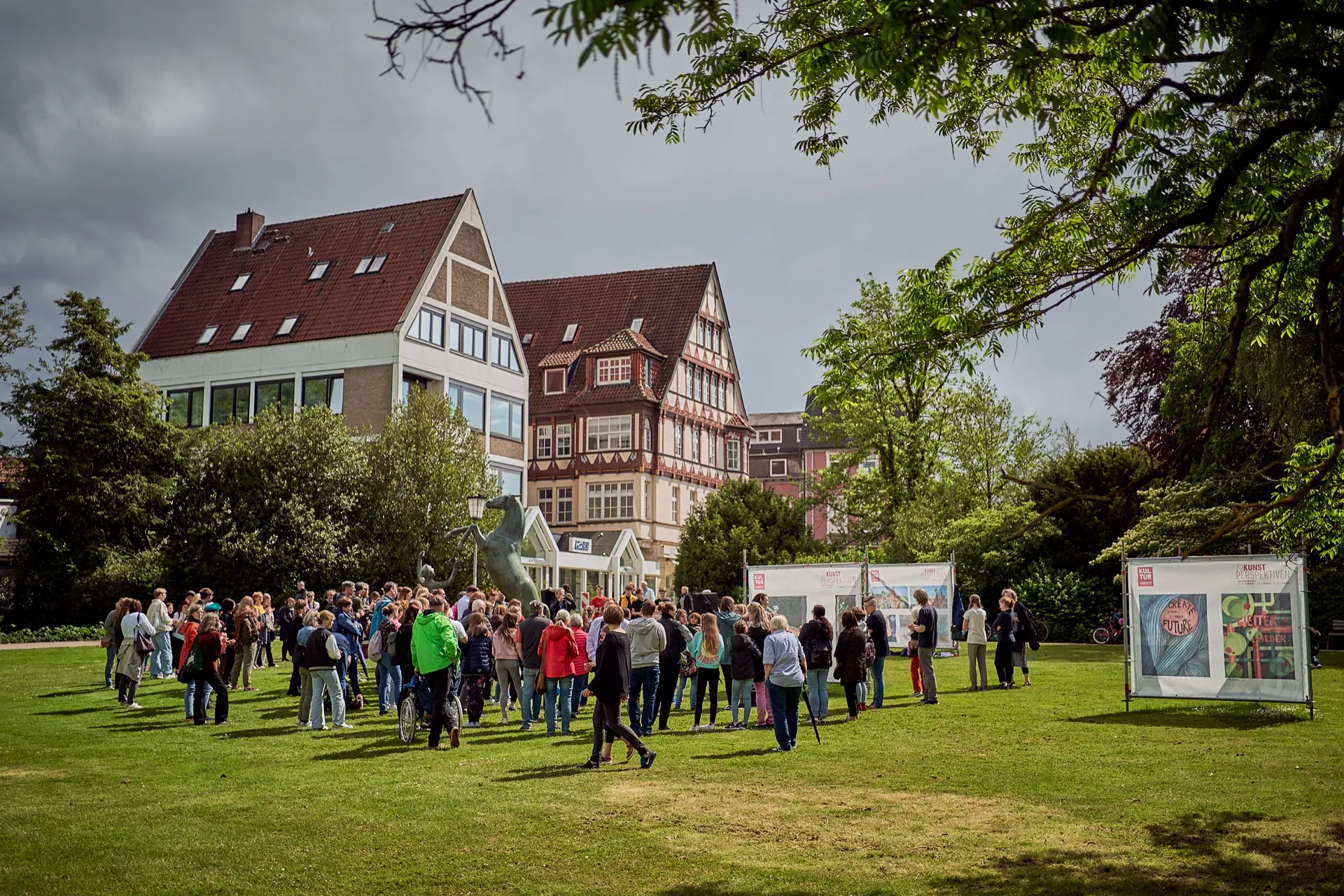 Eine Gruppe steht bei einer Ausstellung im Park zusammen.